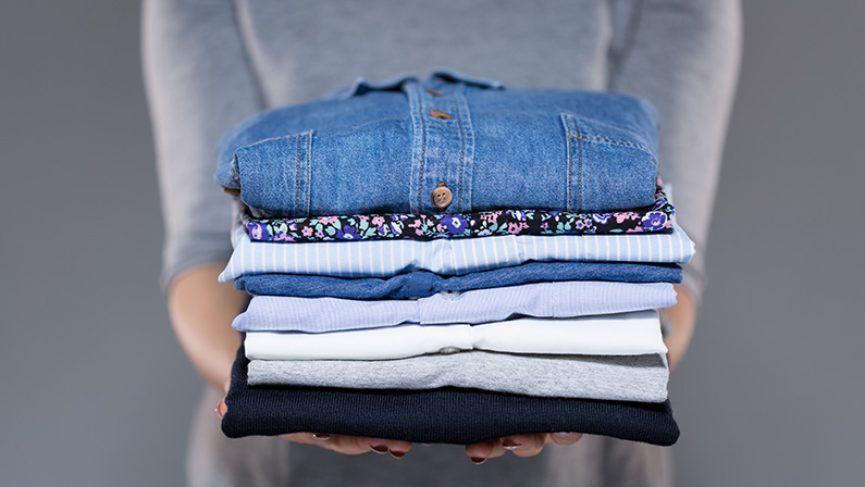 Woman holding folded clothes in hands