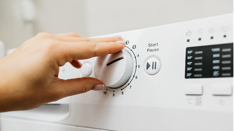 A woman loads dirty laundry into the washing machine and sets the wash cycle. Concept: caring for cleanliness and comfort at home, simplifying daily life with modern technology.